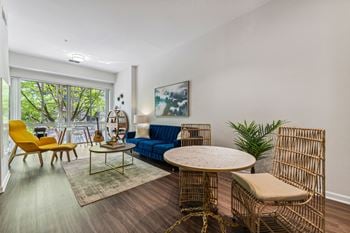 A living room with a blue couch and yellow chairs and a round table