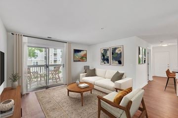 Lorton apartment for rent - A living room with a white couch, a coffee table, and a painting on the wall.