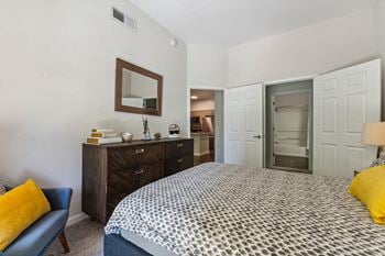 A bedroom with a bed and a dresser and a bathroom