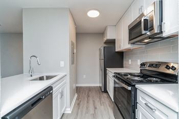 An empty kitchen with white cabinets and stainless steel appliances