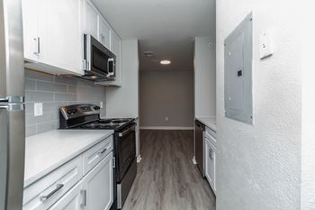 An empty kitchen with white cabinets and a black stove