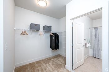 A closet in a bedroom with a door to a shower