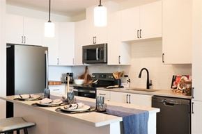 Ashburn apartment for rent - a kitchen with white cabinets and black appliances at Vyne One Loudoun, Virginia, 20147