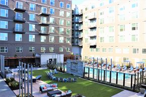 Ashburn apartment for rent - an outdoor lounge area with lounge chairs and a pool next to an apartment building at Vyne One Loudoun, Virginia