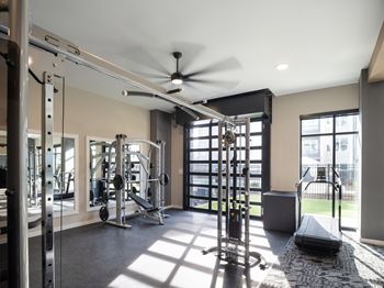 A spacious gym with a variety of equipment and a ceiling fan.