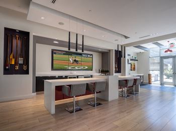 A modern room with a bar and a television playing a baseball game.