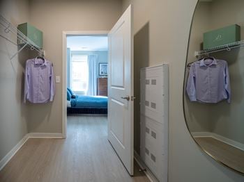 A hallway with a bedroom at the end and two shirts hanging up