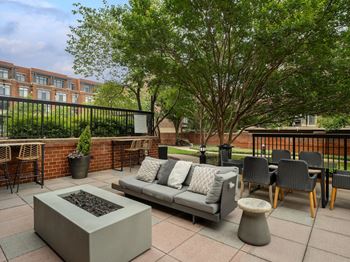 A patio with a couch and chairs and a fire pit