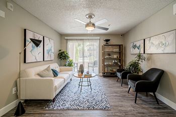 A living room with a white couch, a coffee table, and a ceiling fan.
