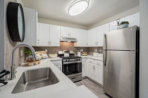 Phoenix apartment for rent - A modern kitchen with a stainless steel refrigerator and a sink with a faucet at Sterling Point Apartment Homes, Phoenix, AZ