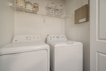 Two white front loading washing machines in a small laundry room.
