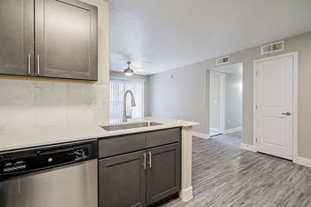 A kitchen with a black dishwasher and a sink with a window above it.
