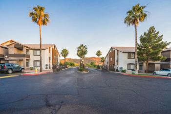 A street view of a residential area with houses and palm trees.