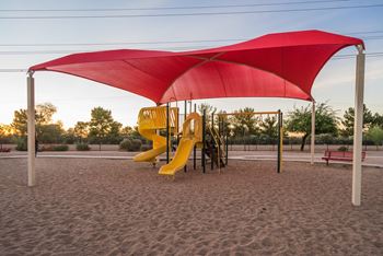 A playground with a red canopy and a yellow slide.