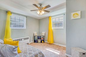 Washington apartment for rent - A bedroom with a bed, a ceiling fan, and yellow curtains at Huntwood Courts Apartments, Washington, DC, 20019
