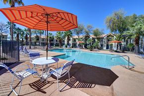 Casa Grande apartment for rent - A pool area with a table and chairs under an orange umbrella.at Cottonwood Crossing, Casa Grande, 85122  