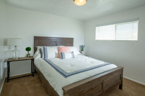 Ogden apartment for rent - A bedroom with a bed, nightstand, and window.at Country Woods, Ogden Utah