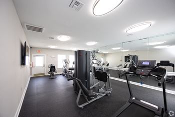A gym with exercise equipment and mirrors in a building