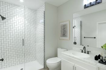 A bathroom with white tiles and a white sink and toilet