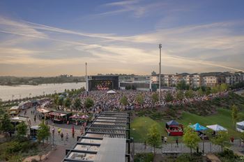 A large crowd is gathered in front of a large stage near a body of water