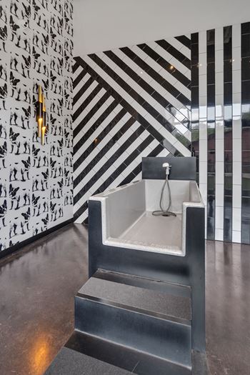 A seating area in a lobby with a black and white wall and a bench