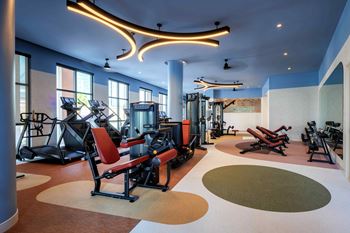 A gym with a variety of equipment including treadmills, weights, and exercise machines
