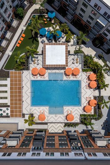 A pool surrounded by orange umbrellas and palm trees