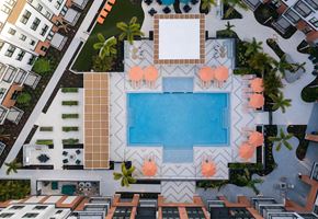Tampa apartment for rent - A swimming pool surrounded by orange chairs and a white table at The Stevedore Apartments in Tampa, FL 33605
