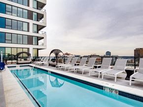 Tysons apartment for rent - a swimming pool with white lounge chairs and a building in the background at The Boro, Tysons, VA