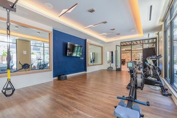 A gym with exercise equipment and a tv on the wall