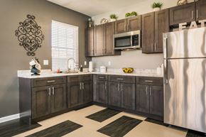 Albuquerque apartment for rent - A kitchen with brown cabinets and a white fridge at West Park Apartments, Albuquerque, NM, 87114
