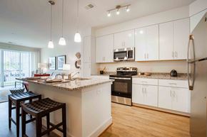 Bowie apartment for rent - a kitchen with white cabinets and a large island with granite countertops  at Woodmore Grand, Bowie, 20721