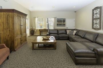 West Jordan apartment for rent - A living room with a brown leather couch and a wooden cabinet.