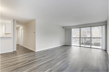 An empty living room with sliding glass doors to a balcony
