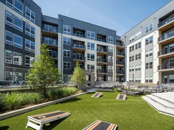 A modern apartment complex with a grassy courtyard and seating area.