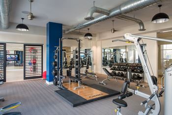 A gym with a variety of equipment including a weight bench and a leg press machine.