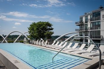 A pool with chairs and a building in the background.