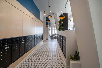 A long hallway with black lockers on the left and a tiled floor.