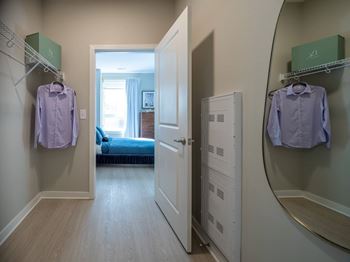 A hallway with a bedroom at the end and two shirts hanging up.