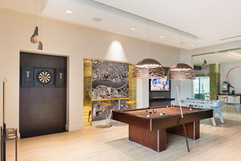A room with a pool table and a dartboard on the wall.
