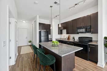 A kitchen with black appliances and a marble counter top