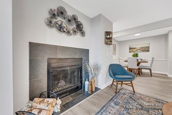 A living room with a fireplace and a dining room in the background