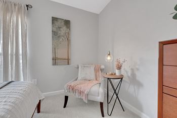 A bedroom with a bed and a nightstand with a vase of flowers