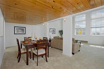 A dining room and living room with a wooden ceiling and a table and chairs