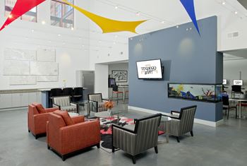 A large lobby with chairs and tables and a tv
