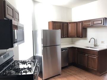 Chicago apartment for rent - A kitchen with a black stove top oven, a silver refrigerator, and brown cabinets.