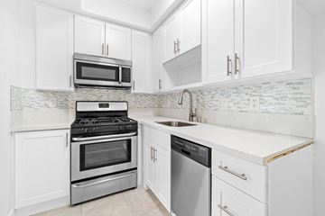 Los Angeles multi-family for rent - a white kitchen with stainless steel appliances and white cabinets