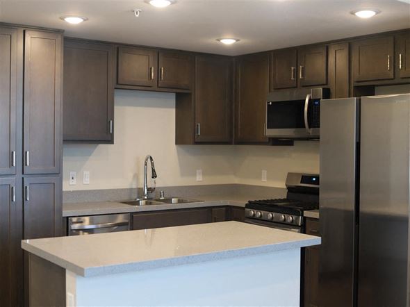 San Bernardino multi-family for rent - a kitchen with a white counter top and a stainless steel refrigerator at Loma Villas Apartments in San Bernardino, CA