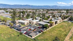 Rialto apartment for rent - A parking lot in front of a building with a mountain in the background. at Heritage Park, Rialto, CA 92376
