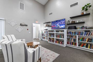 Riverside apartment for rent - A living room with a large bookshelf filled with books and a flat screen TV mounted on the wall.